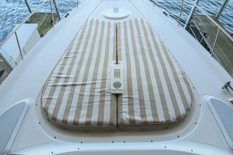 Slide: The Image of 2001 Cruisers Yachts 3672 Express with striped sun pad on deck, docked by water. - 36