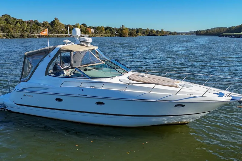 Slide: The Image of 2001 Cruisers Yachts 3672 Express on a serene lake under clear blue skies. - 6