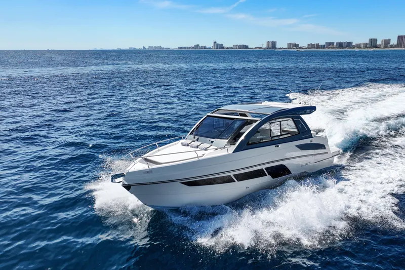 Slide: The Image of 2025 VALIATT YACHTS 380 Bowrider cruising on open ocean with city skyline backdrop. - 23