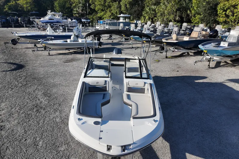 Slide: The Image of 2022 Hurricane SunDeck 235 OB boat displayed in a marina with other vessels. - 10