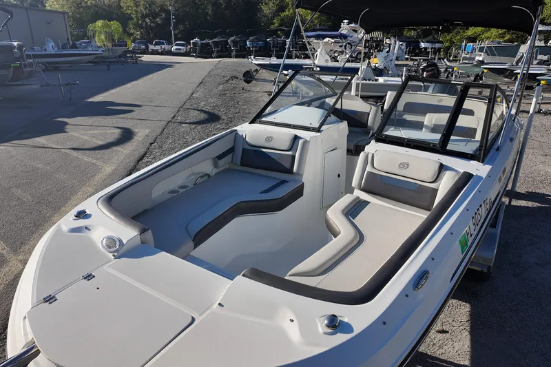 Slide: The Image of 2022 Hurricane SunDeck 235 OB boat with spacious seating and sleek design in a marina. - 16