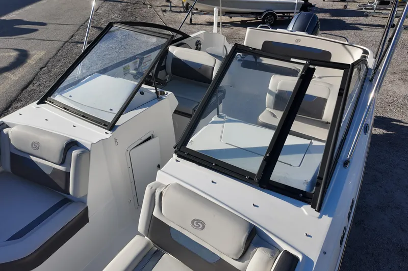Slide: The Image of 2022 Hurricane SunDeck 235 OB boat interior with seating and windshield, parked on gravel. - 17