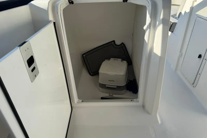 Slide: The Image of 2022 Hurricane SunDeck 235 OB boat storage compartment with portable toilet. - 25