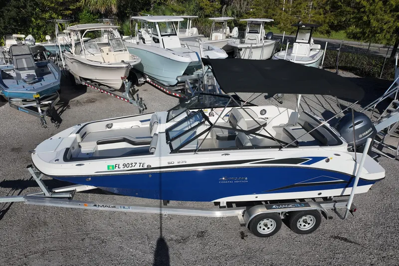 Slide: The Image of 2022 Hurricane SunDeck 235 OB boat on trailer, surrounded by other boats. - 3
