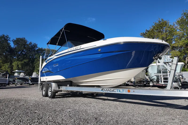 Slide: The Image of 2022 Hurricane SunDeck 235 OB boat on trailer, blue and white design, parked outdoors. - 4