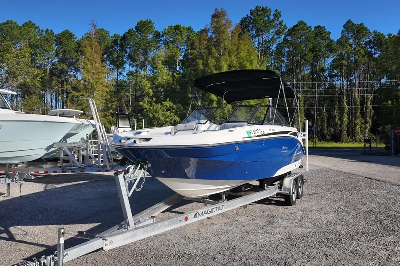 Slide: The Image of 2022 Hurricane SunDeck 235 OB boat on trailer, parked outdoors with trees in background. - 5