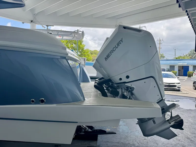 Slide: The Image of 2025 Intrepid 41 Panacea boat with Mercury outboard motor, docked under a canopy. - 2