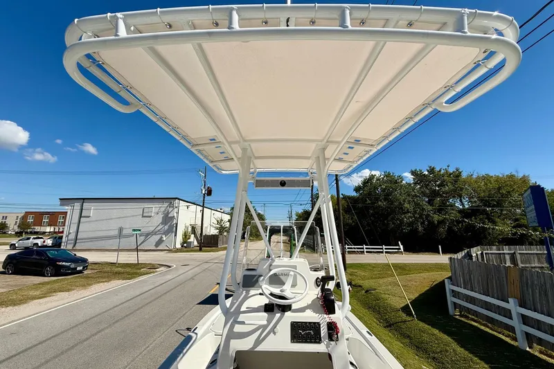 Slide: The Image of 2024 Shallow Sport 24 Modified V boat with T-top on a sunny street. - 11
