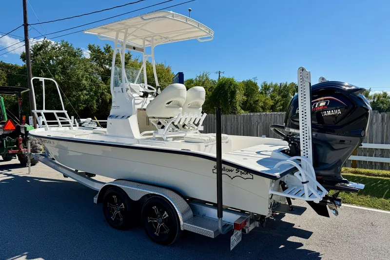 Slide: The Image of 2024 Shallow Sport 24 Modified V boat on trailer with Yamaha engine, parked outdoors. - 2