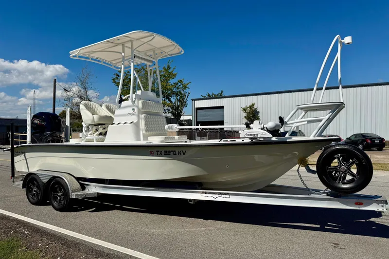 Slide: The Image of 2024 Shallow Sport 24 Modified V boat on trailer, parked outdoors under clear sky. - 5