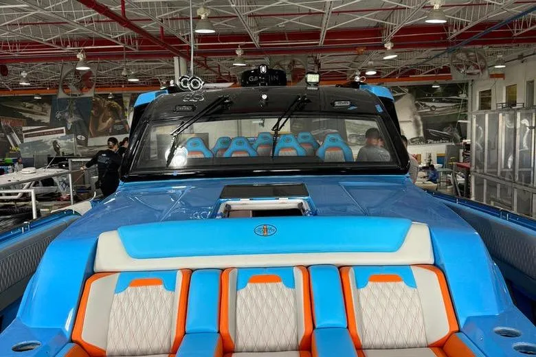 Slide: The Image of 2025 Cigarette 52 Thunder boat with vibrant blue and orange seating in a showroom. - 8