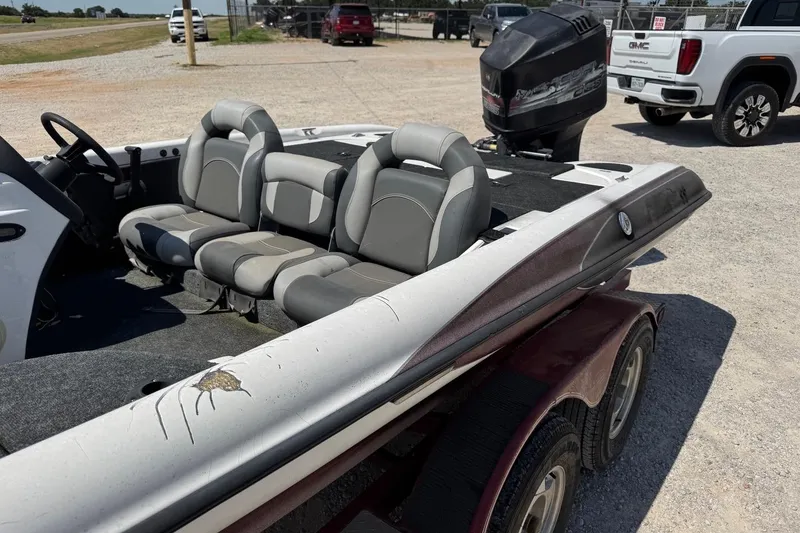 Slide: The Image of 2000 Triton TR-21 boat with gray seating and outboard motor, parked on gravel. - 4