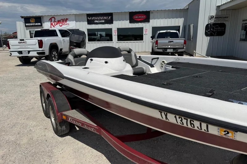 Slide: The Image of 2000 Triton TR-21 boat on trailer, parked outside dealership with trucks in background. - 9