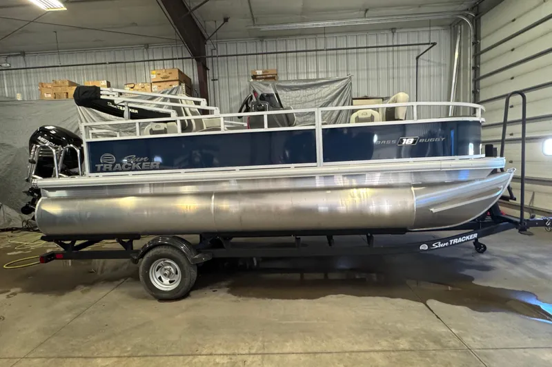 Slide: The Image of 2026 Sun Tracker Bass Buggy 18 DLX pontoon boat in a garage setting. - 3