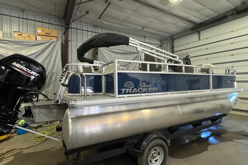 Slide: The Image of 2026 Sun Tracker Bass Buggy 18 DLX pontoon boat in a garage setting. - 4