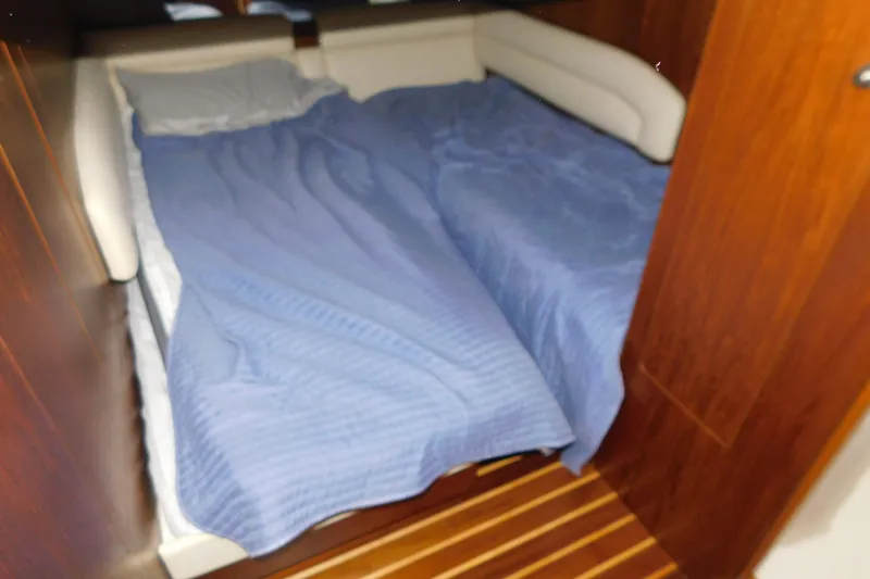 Slide: The Image of 2009 Tiara Yachts 4300 Sovran cabin with blue bedding and wooden interior. - 36