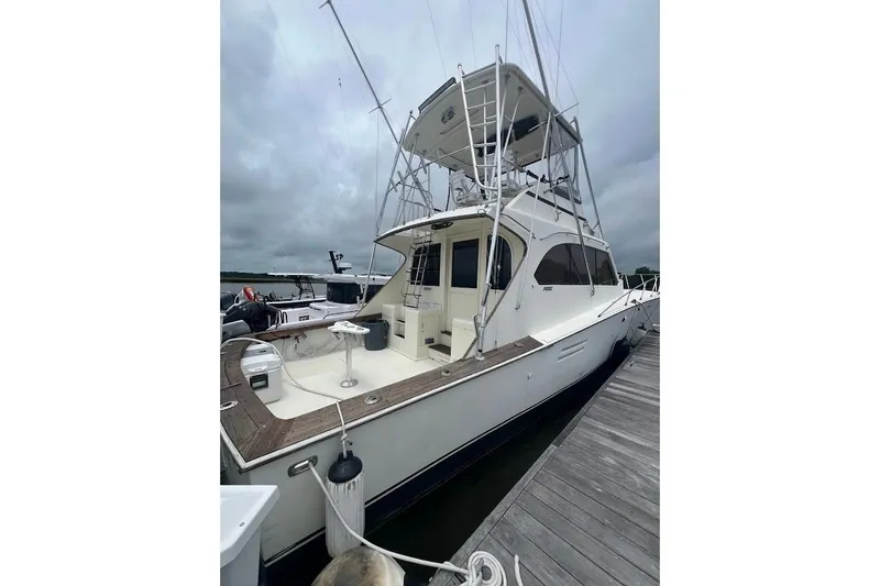 Slide: The Image of 1988 Post 46 ll yacht docked, featuring a spacious deck and flybridge under cloudy skies. - 23