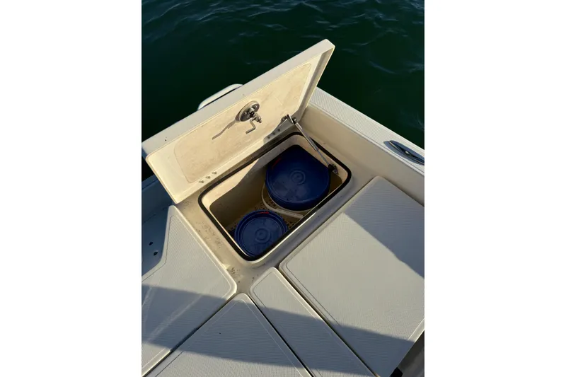Slide: The Image of 2017 Skeeter SX230 boat storage compartment with blue containers, open on deck. - 17