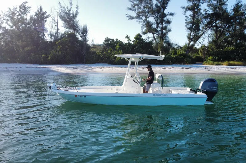 Slide: The Image of 2017 Skeeter SX230 boat on clear water near a sandy beach with trees. - 2