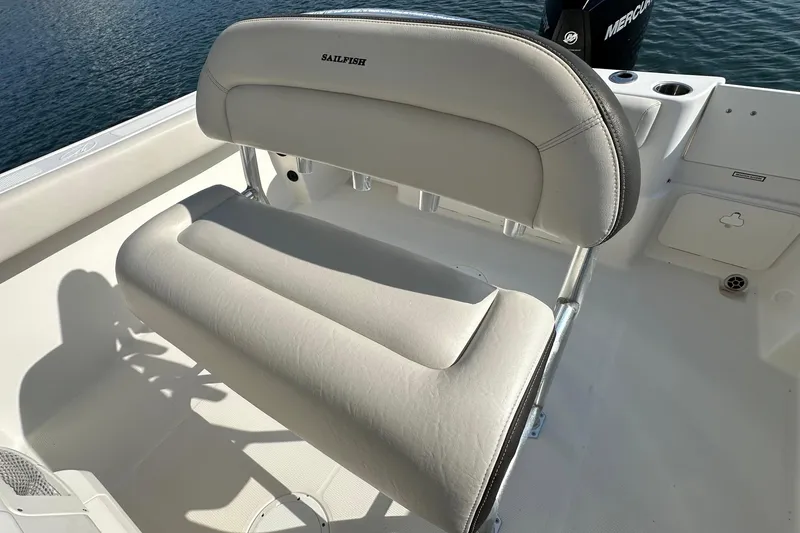 Slide: The Image of 2022 Sailfish 242 CC boat seat with white upholstery, set against a calm water backdrop. - 11