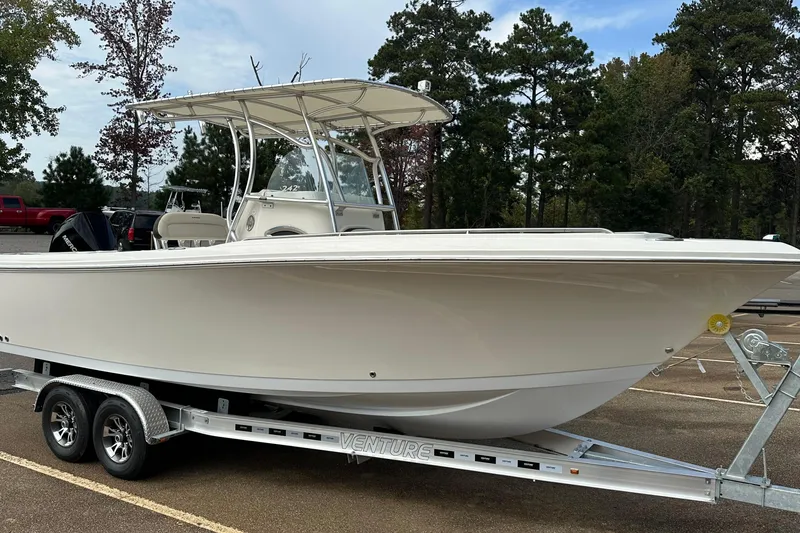 Slide: The Image of 2022 Sailfish 242 CC boat on trailer in parking lot, surrounded by trees. - 4