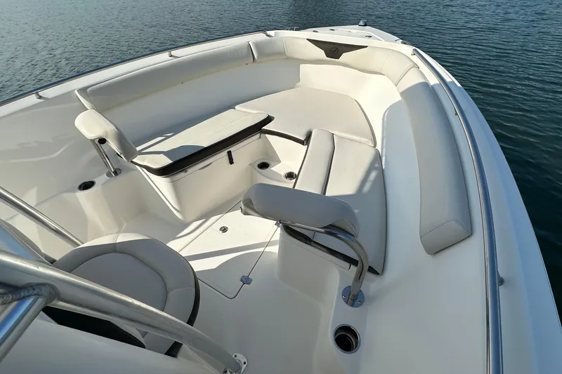 Slide: The Image of 2022 Sailfish 242 CC boat interior with cushioned seating and table on calm water. - 8