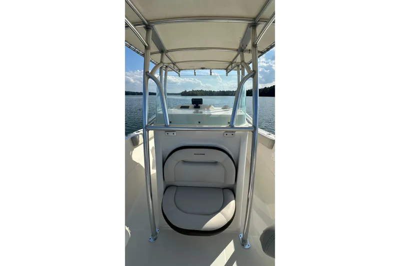 Slide: The Image of 2022 Sailfish 242 CC boat interior with seating and canopy on a calm lake. - 9