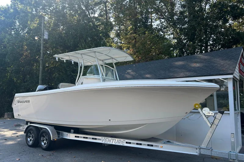 Slide: The Image of 2022 Sailfish 242 CC boat on trailer, parked outdoors near trees. - 14