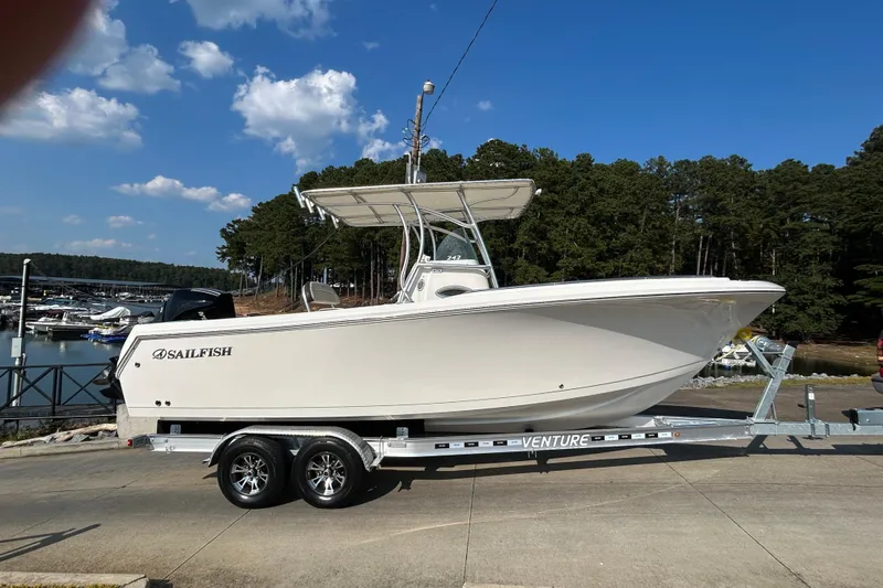 Slide: The Image of 2022 Sailfish 242 CC boat on trailer, parked near marina under clear blue sky. - 16