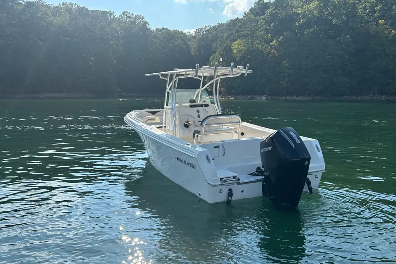 Slide: The Image of 2022 Sailfish 242 CC boat on calm lake with forested shoreline. - 3