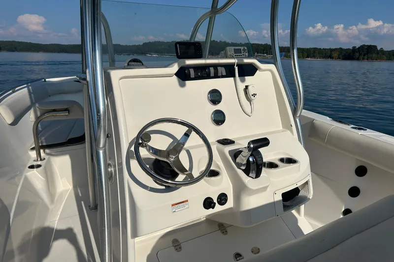Slide: The Image of 2022 Sailfish 242 CC boat console with steering wheel and controls on a sunny day. - 7