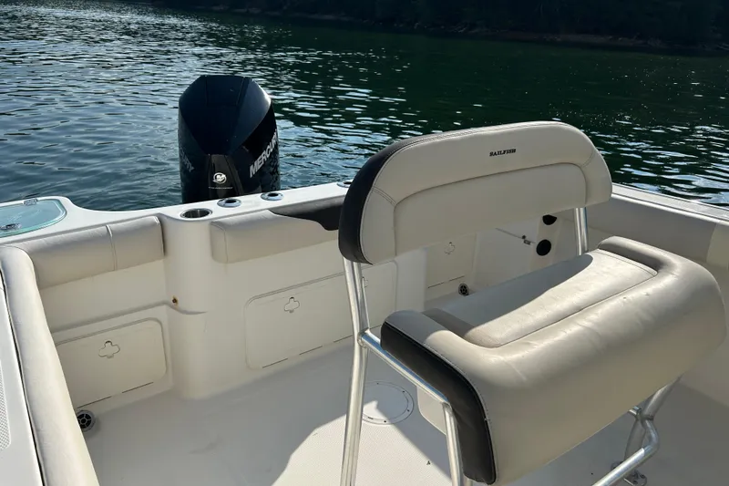 Slide: The Image of 2022 Sailfish 242 CC boat interior with seating and Mercury outboard motor on a calm lake. - 9