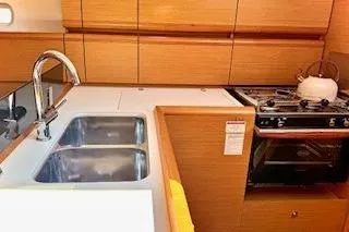 Slide: The Image of 2013 Jenneau Sun Odyssey 379 yacht kitchen with sink, stove, and wooden cabinetry. - 28