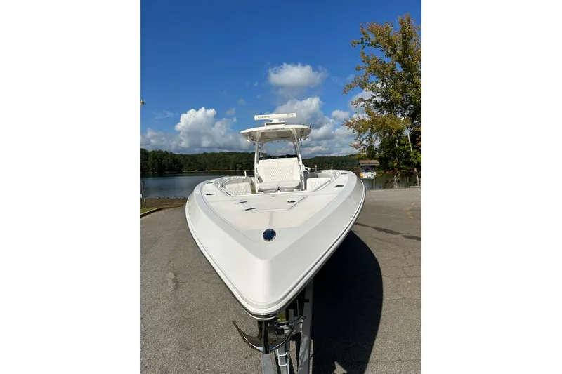 Slide: The Image of 2022 Fountain 38 CC LS boat on trailer, parked near a scenic lake under a clear blue sky. - 10