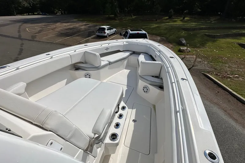Slide: The Image of 2022 Fountain 38 CC LS boat interior with white seating and speakers in a parking area. - 13