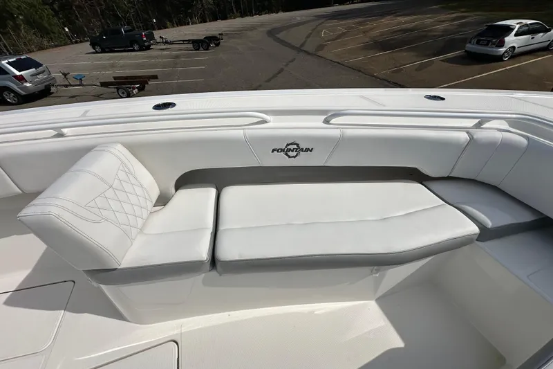 Slide: The Image of 2022 Fountain 38 CC LS boat with white cushioned seating in a parking lot. - 14