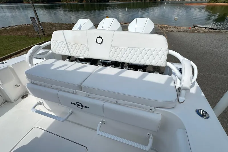 Slide: The Image of 2022 Fountain 38 CC LS boat with white seating, docked by a serene lake. - 19
