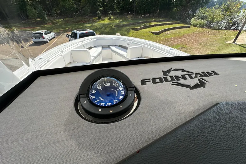 Slide: The Image of 2022 Fountain 38 CC LS boat dashboard with compass, parked near a scenic lake. - 37