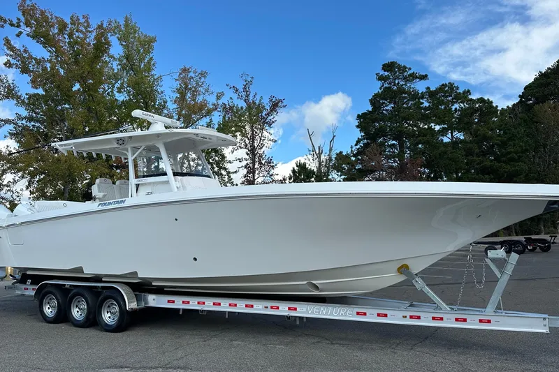Slide: The Image of 2022 Fountain 38 CC LS boat on trailer, parked outdoors with trees in background. - 7
