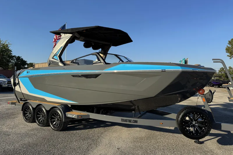 The Image of 2026 Tigé Ultré 25ZX boat on trailer, featuring sleek design and vibrant blue accents. - 1
