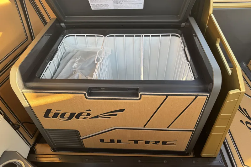 Slide: The Image of 2026 Tigé Ultré 25ZX onboard cooler with open lid, showcasing interior storage space. - 12