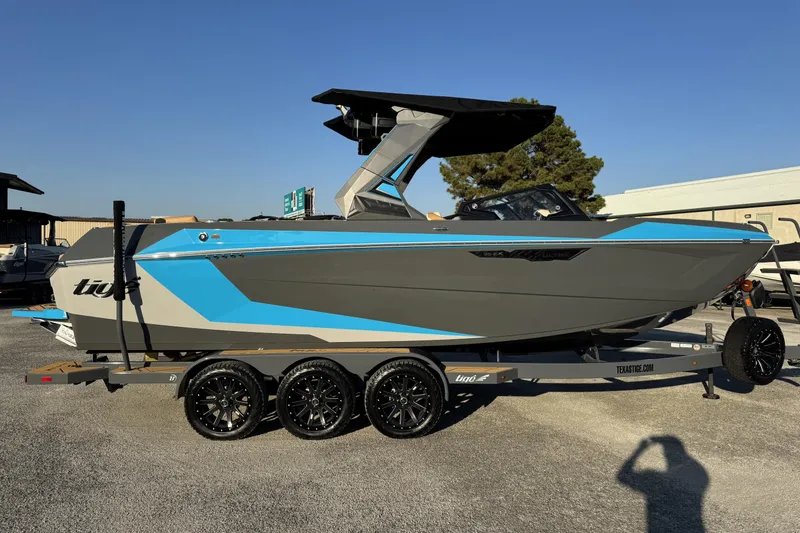 Slide: The Image of 2026 Tigé Ultré 25ZX boat on trailer, featuring sleek gray and blue design. - 2