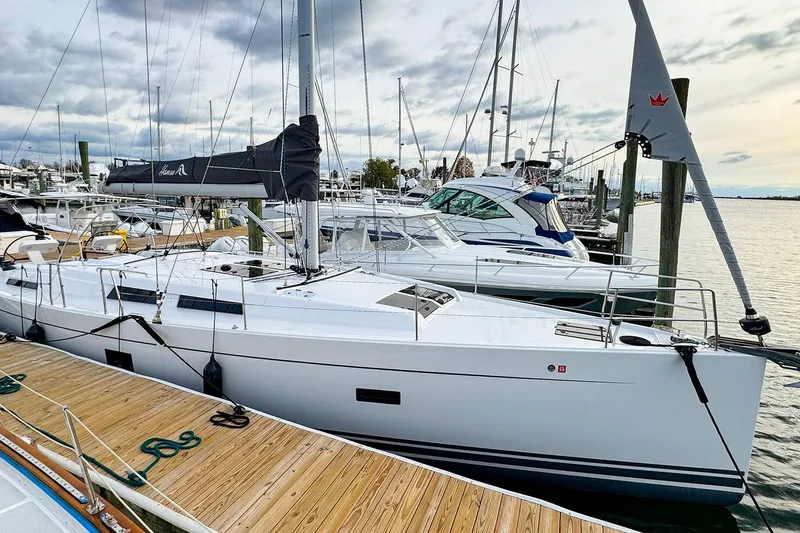 Slide: The Image of 2025 Hanse 458 yacht docked at marina, surrounded by other boats under cloudy sky. - 0