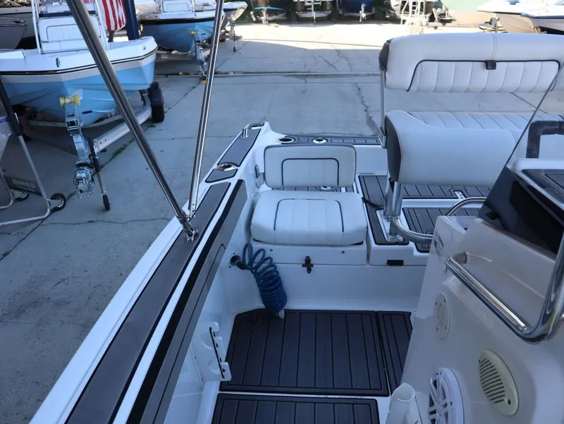 Slide: The Image of 2019 Yamaha Boats 210 FSH Sport interior with white seating and deck details. - 16