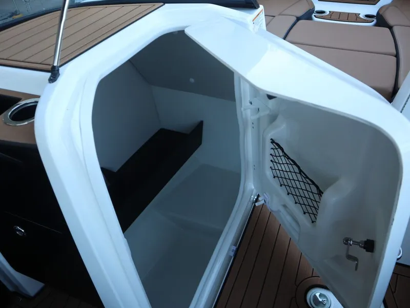 Slide: The Image of 2026 Yamaha Boats 252SD storage compartment with open door and netted pocket. - 13