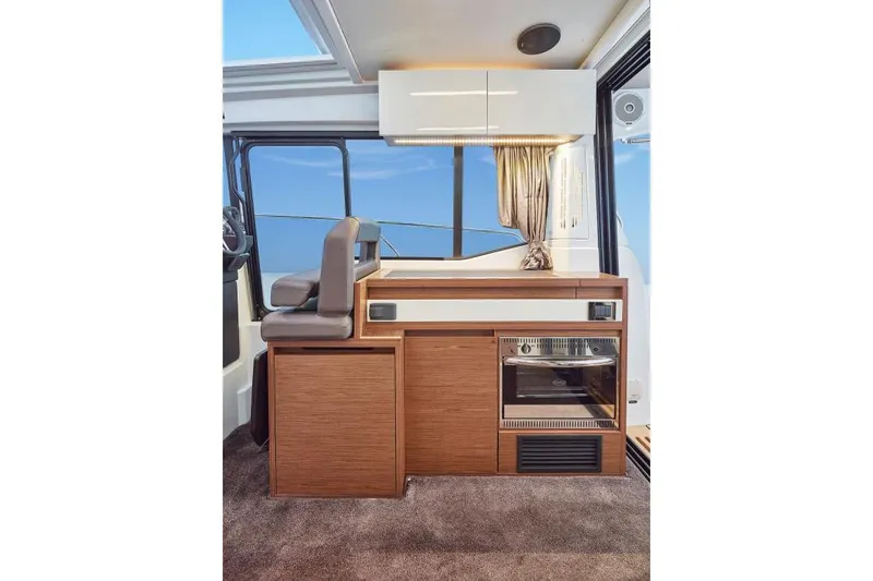 Slide: The Image of 2019 Jeanneau Leader 33 helm with steering wheel, navigation controls, and comfortable seating. - 13