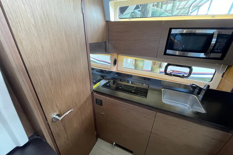 Slide: The Image of 2019 Jeanneau Leader 33 yacht kitchen with modern appliances and sleek wood cabinetry. - 23