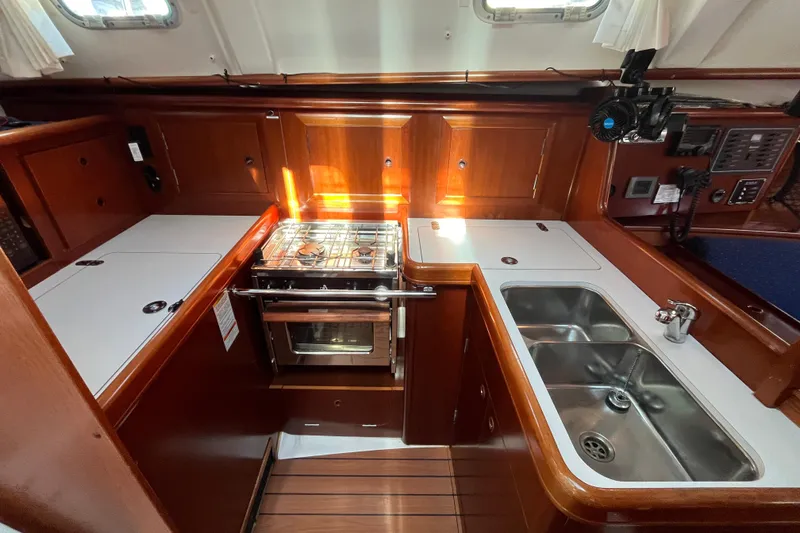Slide: The Image of 2004 Beneteau 331 yacht kitchen with stove, sink, and wooden cabinetry. - 16