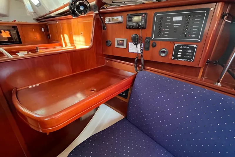 Slide: The Image of 2004 Beneteau 331 yacht interior with navigation station and blue cushioned seating. - 21