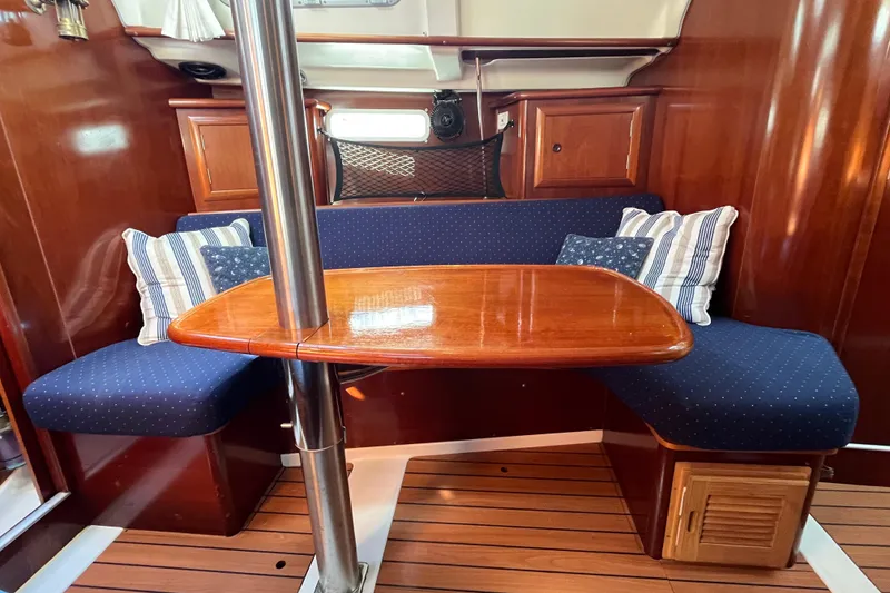 Slide: The Image of 2004 Beneteau 331 sailboat interior with wooden table, blue cushioned seating, and striped pillows. - 22